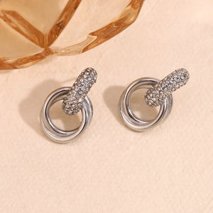 Pair of silver earrings with intricate designs on a beige background