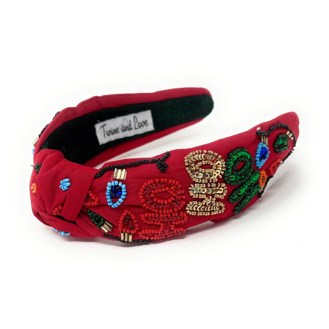 Red headband adorned with colorful beaded designs. The festive patterns create a cheerful, holiday-inspired look against a white background.