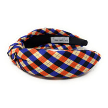 Load image into Gallery viewer, Colorful headband with a plaid pattern in red, blue, and beige hues against a white background. The fabric is knotted in the center, creating a playful and trendy accessory.