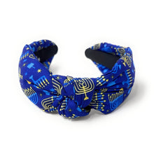 Load image into Gallery viewer, A fabric twist-front headband featuring a royal blue background with a gold and light blue menorah and star pattern, displayed on a clean white background.