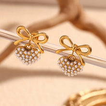 Load image into Gallery viewer, 18k Gold plated earrings with heart designs and pearl accents on a beige background