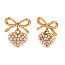 Load image into Gallery viewer, 18k Gold plated earrings with bow and pearl details on a textured beige surface