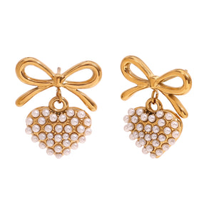 18k Gold plated earrings with bow and pearl details on a textured beige surface