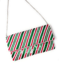 Load image into Gallery viewer, A festive clutch purse adorned with diagonal red, green, and white sequin stripes, creating a vibrant, shimmering pattern that evokes holiday cheer.