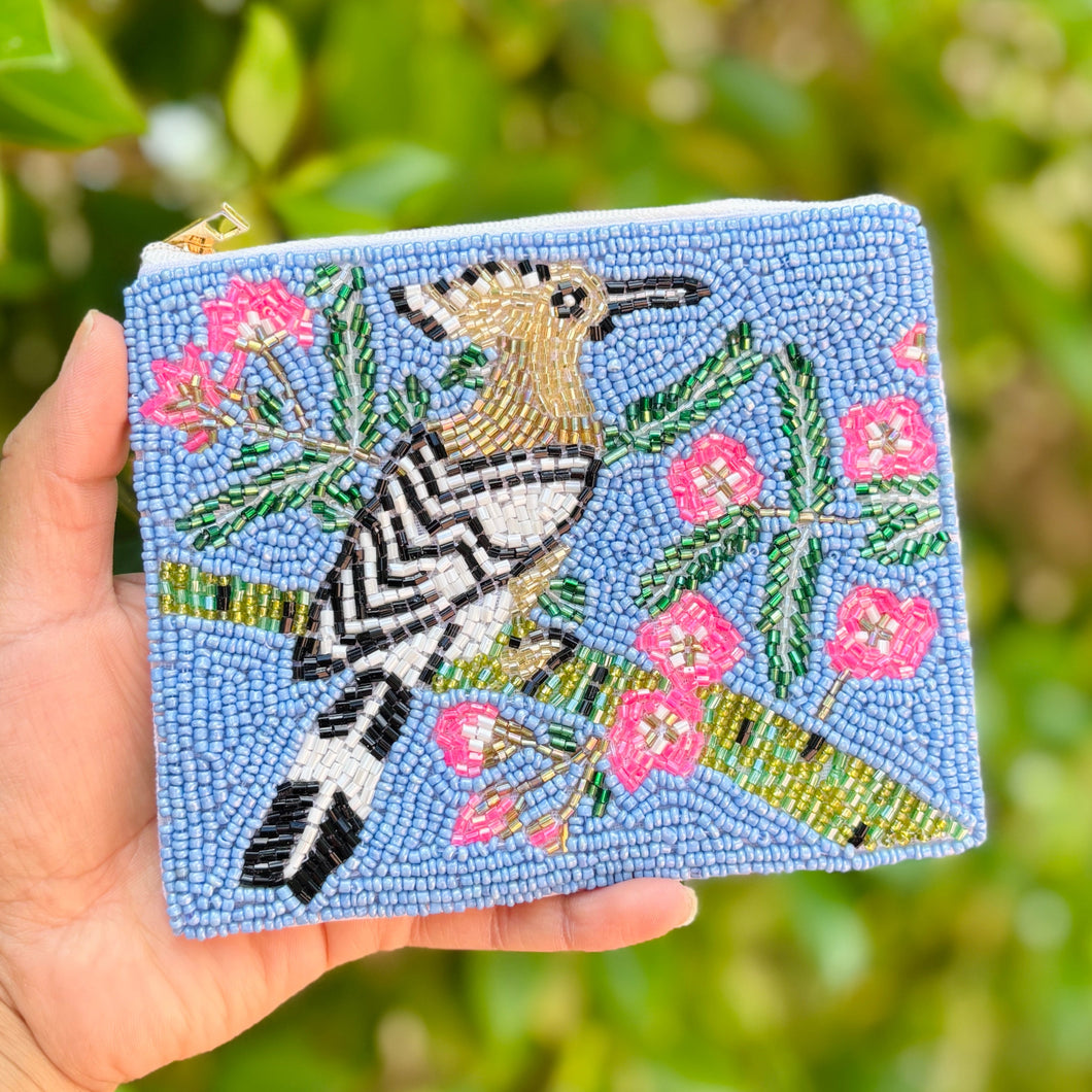 Hand Beaded purse pouch with a hoopoe bird design. Features a brown bird with black and white stripes perched on a branch, surrounded by pink flowers on a blue background.
