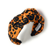 Load image into Gallery viewer, Orange knotted headband with black Halloween-themed prints, featuring pumpkins and cats. The design is playful, capturing a festive Halloween vibe.