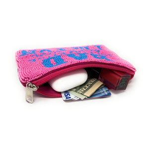 Pink pouch with blue patterns containing a white object, money, and a phone on a white background