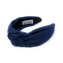 Load image into Gallery viewer, A dark blue denim fabric headband with a centered knot design sits on a white background. The soft texture and simple style convey a casual, elegant tone.