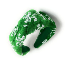 Load image into Gallery viewer, Green velvet headband adorned with white snowflake patterns. The texture is soft and plush, giving a festive, cheerful vibe against a plain white background.