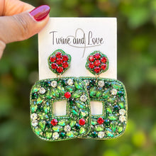 Load image into Gallery viewer, Green and red earrings held on a card with a blurred green background