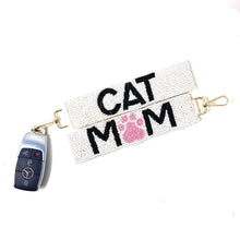 Load image into Gallery viewer, White beaded keychains with "CAT MOM" in black letters, featuring a pink paw print. Gold clasps attached. Playful and pet-themed design.