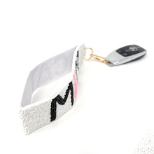 Load image into Gallery viewer, White beaded bracelet with black lettering and a car key fob on a white background