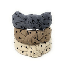 Load image into Gallery viewer, Three knotted headbands in gray, beige, and white with black heart patterns on a white background.