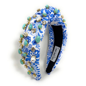 A blue and white floral-patterned headband adorned with turquoise stones and sparkling gems. It conveys a vibrant, elegant, and artistic flair.