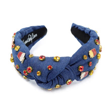 Load image into Gallery viewer, A blue denim headband with a knot design, decorated with red, gold, and clear rhinestones and small enamel fast-food-themed pins, including fries and sodas.