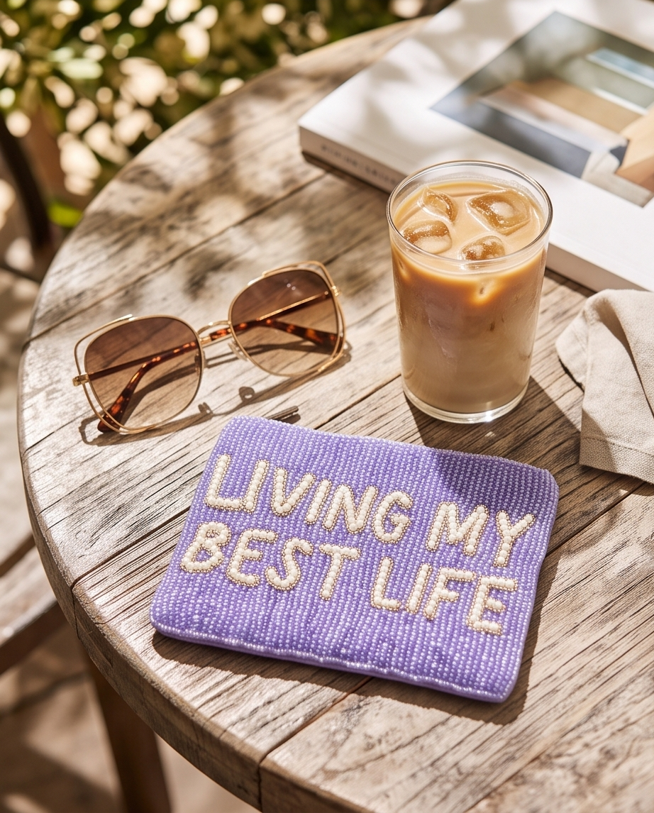 Lavender beaded pouch with Living My Best Life lettering, styled with tortoiseshell sunglasses and an iced latte.