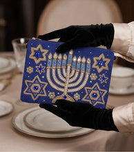 Load image into Gallery viewer, Hand holding a blue and gold Hanukkah beaded clutch, perfect for holiday celebrations.