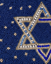 Load image into Gallery viewer, Close-up lifestyle view of a hand holding a navy blue beaded Star of David pouch with sparkling crystal embellishments.