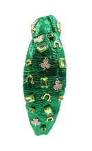 Load image into Gallery viewer, headbands for women, green knotted headband, headband style, top knot headband, green top knot headband, lucky charm jeweled headband, lucky charm hair band, green Jeweled knot headband, St Patrick’s Jeweled headband, top knotted headband, hand bead knotted headband, Clover leaf hair band for women, St Patrick’s Embellished headband, statement headbands, embellished headband, chic headband, clover leaf knot headband, st paddy’s headband, green hair accessories, four leaf clover headband, shamrock headband
