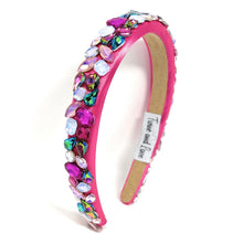 Load image into Gallery viewer, A vibrant pink headband adorned with multicolored gemstones, including blue, purple, and green. It exudes a playful, glamorous vibe.