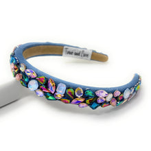 Load image into Gallery viewer, A vibrant, gemstone-encrusted headband with a blue fabric base adorned with multicolored jewels, including blue, purple, and gold, emanating a luxurious and playful vibe.