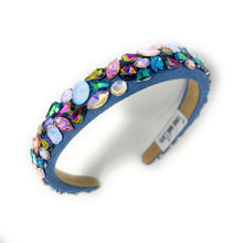 Load image into Gallery viewer, A vibrant, gemstone-encrusted headband with a blue fabric base adorned with multicolored jewels, including blue, purple, and gold, emanating a luxurious and playful vibe.