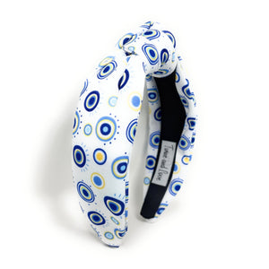 A white padded headband features a blue and yellow concentric circle pattern, exuding a playful vibe.
