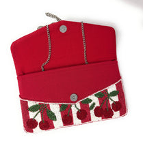 Load image into Gallery viewer, A red fabric clutch purse with a cherry-themed embroidered flap. The flap features red and white stripes with embroidered cherries, green leaves, and stems, and is secured with a silver snap button.