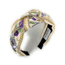 Load image into Gallery viewer, Elegant, floral-embroidered headband with gold detailing and a label inside. Features purple and sage green flowers on a cream background.
