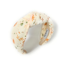 Load image into Gallery viewer, ivory-colored headband with a floral pattern in orange and green. It has a knotted design and visible label inside. Elegant and playful tone.