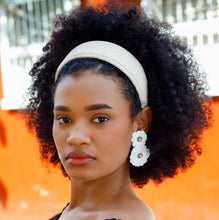 Load image into Gallery viewer, Woman with natural curly hair wearing a wide ivory woven headband and white floral statement earrings, styled with an elegant black off-the-shoulder dress.
