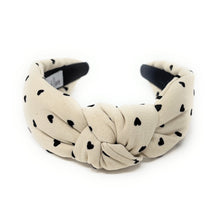 Load image into Gallery viewer, Cream headband with black heart patterns on a white background