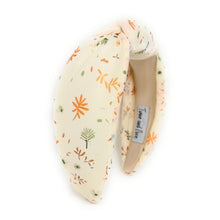 Load image into Gallery viewer, Ivory-colored headband with a floral pattern in orange and green. It has a knotted design and visible label inside. Elegant and playful tone.