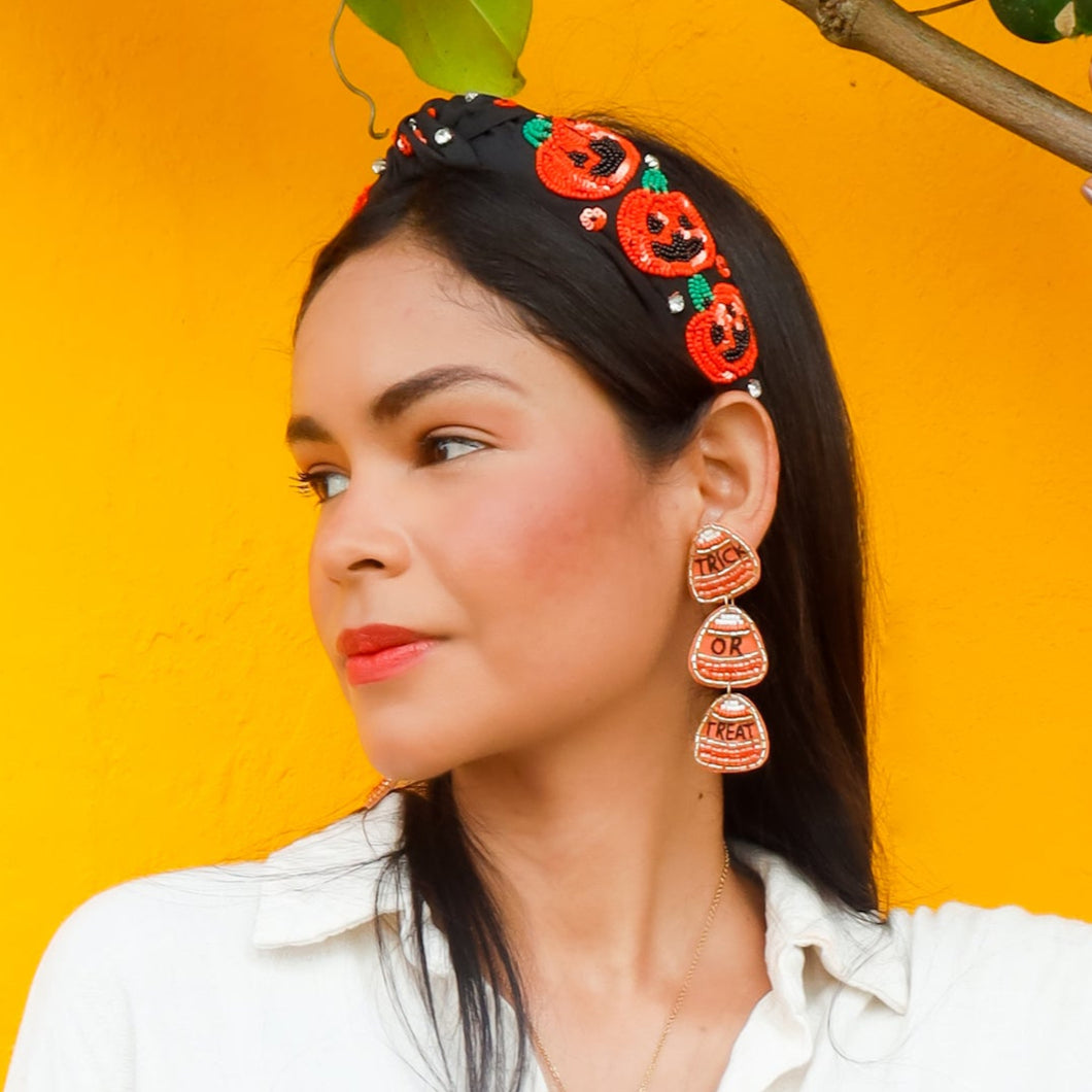 Woman wearing a white shirt and a halloween headband against a yellow background