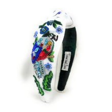 Load image into Gallery viewer, White hand-beaded knotted headband featuring a colorful jeweled bird, blue flowers, green leaves, and sparkling crystal embellishments. Handmade statement hair accessory by Twine and Love.