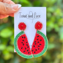 Load image into Gallery viewer, Colorful beaded watermelon dangle earrings held against green background
