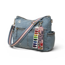 Load image into Gallery viewer, Denim handbag with colorful strap and text tag on a white background