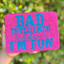 Load image into Gallery viewer, Pink pouch with blue text held by a hand against a blurred green background