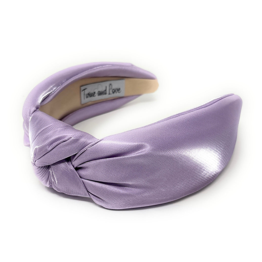 Lavender satin headband with a knot detail, showcasing a shiny texture. The interior reads 