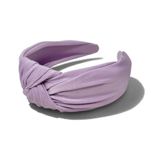 Load image into Gallery viewer, A lavender satin twist-front headband with a knotted center detail, displayed on a clean white background with a soft shadow.