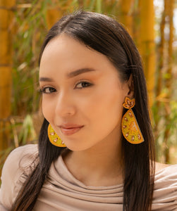 Woman wearing beautiful handcrafted yellow earrings with a blurred natural background