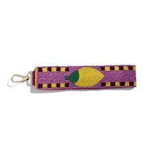 Load image into Gallery viewer, A purple beaded keychain featuring a yellow lemon design with a green stem, attached to a gold metal lobster clasp, shown on a plain white background.