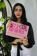Load image into Gallery viewer, Woman holding a pink clutch with &#39;Let&#39;s Go Girls&#39; text and a pink hat graphic.