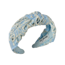 Load image into Gallery viewer, Light blue padded headband with intricate white floral embroidery, displayed in a side view. The soft texture and elegant design convey a stylish, timeless appeal.