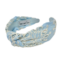 Load image into Gallery viewer, Light blue headband with intricate white floral embroidery, displayed in a side view. The soft texture and elegant design convey a stylish, timeless appeal.