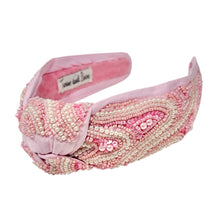 Load image into Gallery viewer, Pink padded headband adorned with intricate beadwork in swirling patterns. It features a central knot, creating an elegant and textured design.