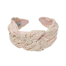 Load image into Gallery viewer, Light pink headband with intricate white floral embroidery. The soft texture and elegant design convey a stylish, timeless appeal.