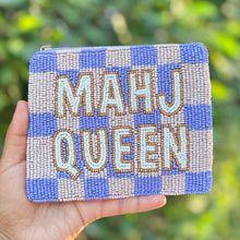 Load image into Gallery viewer, A hand holds a square beaded coin purse with a blue and beige checkered pattern and the words 'MAHJ QUEEN' in raised lettering, set against a blurred green outdoor background.