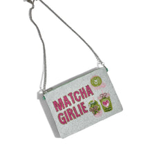 Load image into Gallery viewer, A light green rectangular clutch bag with a silver chain strap, featuring the text 'MATCHA GIRLIE' in pink and green illustrations of matcha green tea bags on a white background.