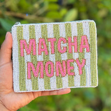 Load image into Gallery viewer, A hand holding a small zippered pouch with a green and white striped pattern and pink text reading 'MATCHA MONEY' against a blurred green outdoor background.